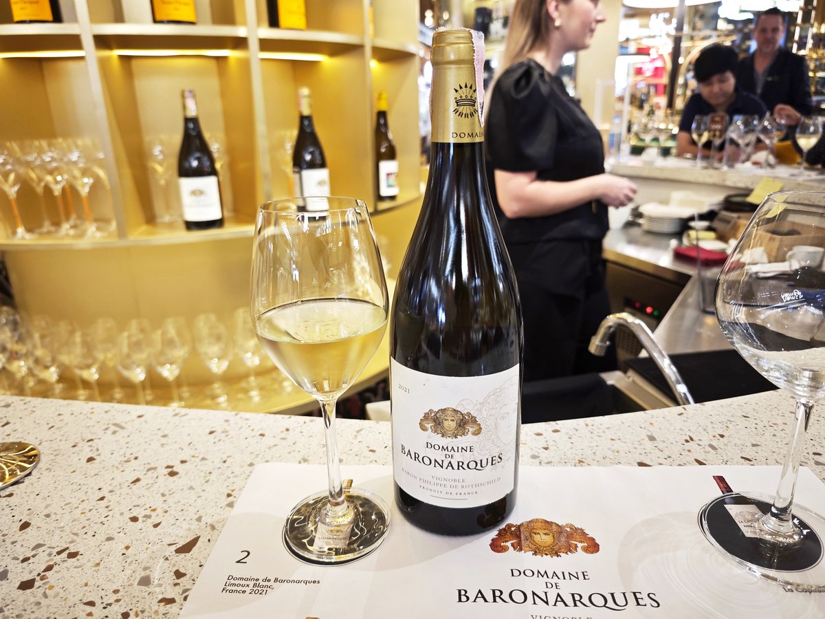 ขวดไวน์ขาว Domaine de Baronarques Blanc 2021  วางเคียงคู่แก้วไวน์บนแผ่นรอง Tasting Mat ที่ chanmpange bar ใน Tops Central Park รีวิวโดย ReviewNowz