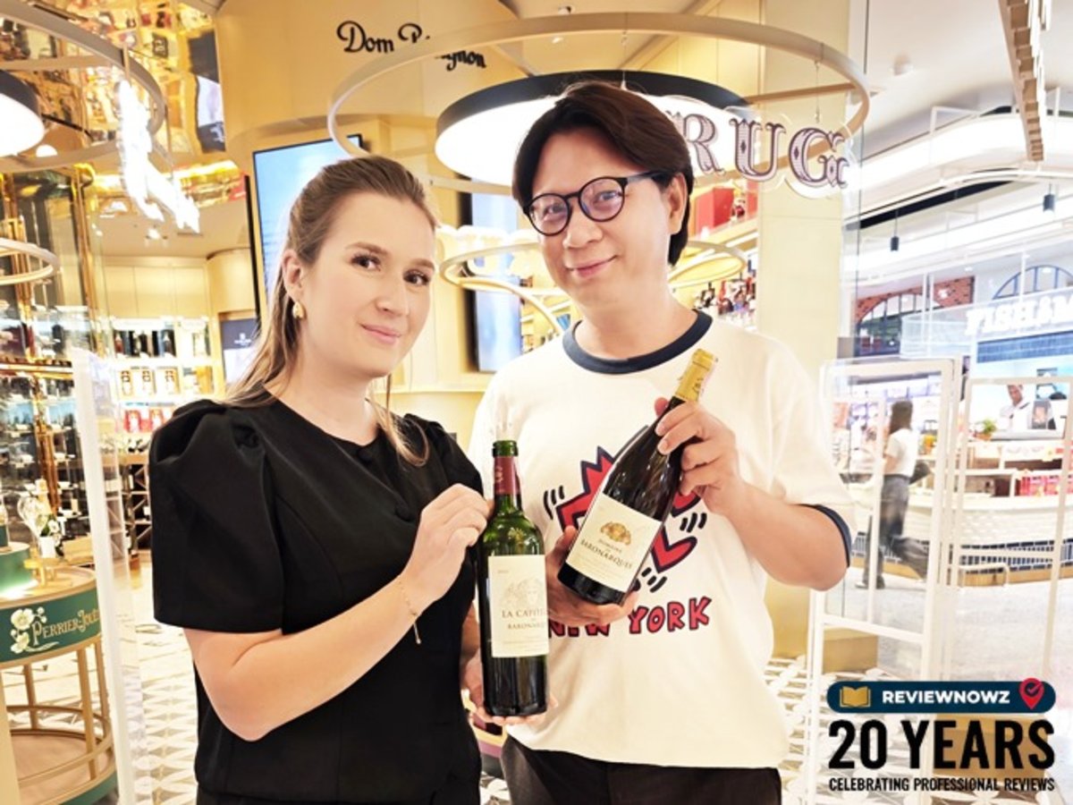 ภาพถ่ายคู่ระหว่าง คุณ Perrine Shaeffer (Export Manager ของ Domaine de Baronarques) แลตคุณโด้ ReviewNowz ถือขวดไวน์แดงและไวน์ขาวร่วมกันด้วยรอยยิ้มอย่างเป็นกันเอง ในงานไวน์เทสติ้งที่ Tops Central Park