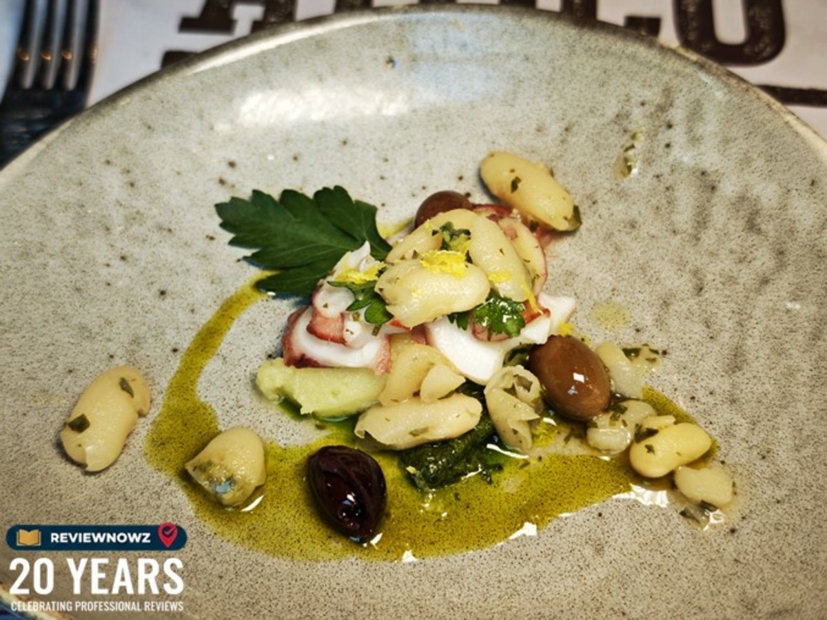 เมนู Octopus carpaccio เสิร์ฟพร้อมถั่วขาวเนื้อนุ่ม มะกอกดอง และสมุนไพรสด ราดด้วยน้ำมันมะกอกชั้นดี จัดจานอย่างประณีตในชามเซรามิกสีครีมเทา สำหรับงานรีวิวอาหาร ณ ห้องอาหาร Attico โรงแรม Radisson Blu Plaza Bangkok