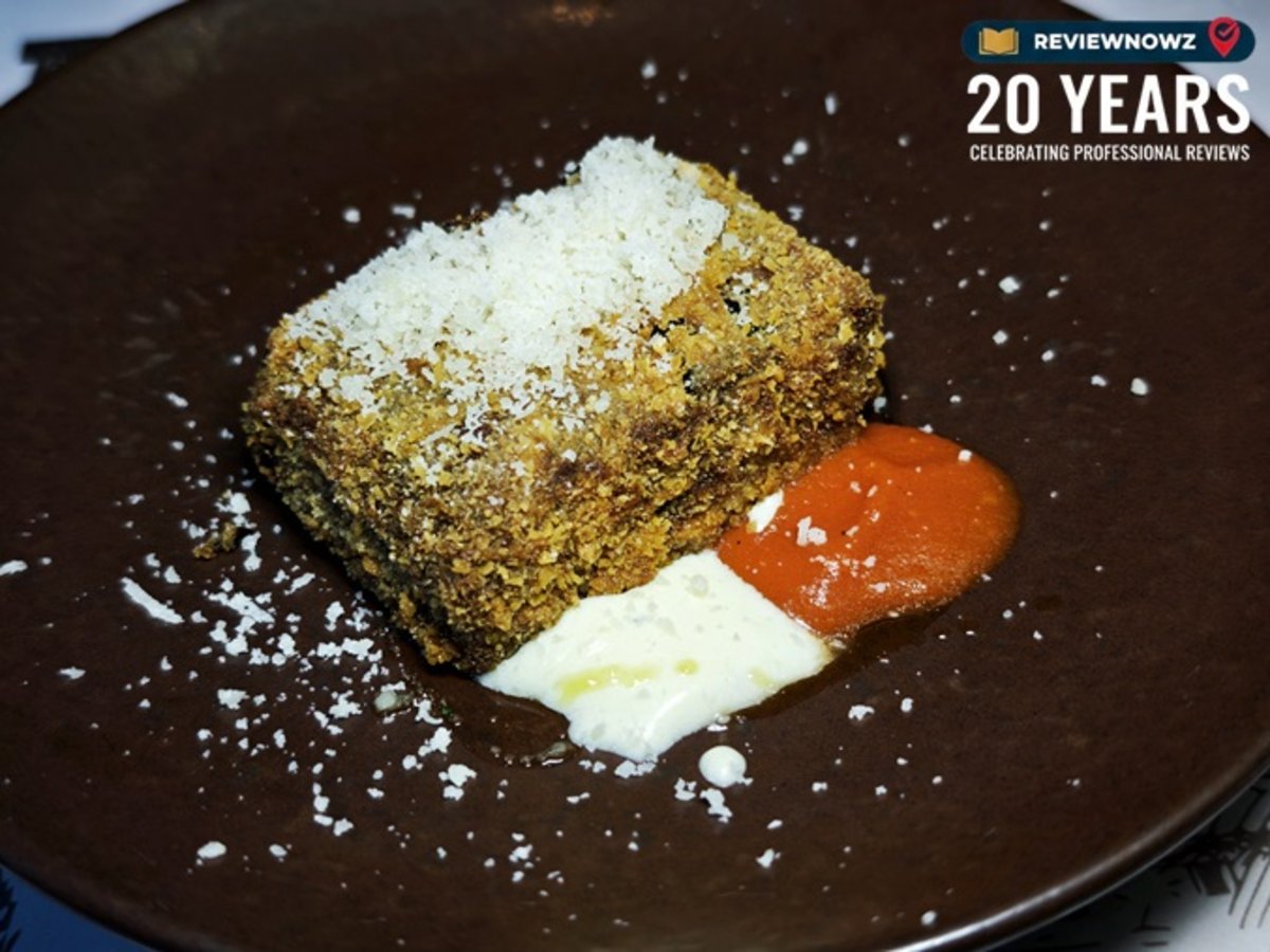 เมนู Crispy eggplant parmigiana cube มะเขือยาวชุบแป้งทอดกรอบทรงสี่เหลี่ยมลูกบาศก์หนา โรยหน้าด้วยพาร์เมซานชีสฝอย เสิร์ฟพร้อมซอสมะเขือเทศและพาร์เมซานฟอนดูบนจานสีน้ำตาลเข้ม สำหรับงานรีวิวอาหาร ณ ห้องอาหาร Attico โรงแรม Radisson Blu Plaza Bangkok
