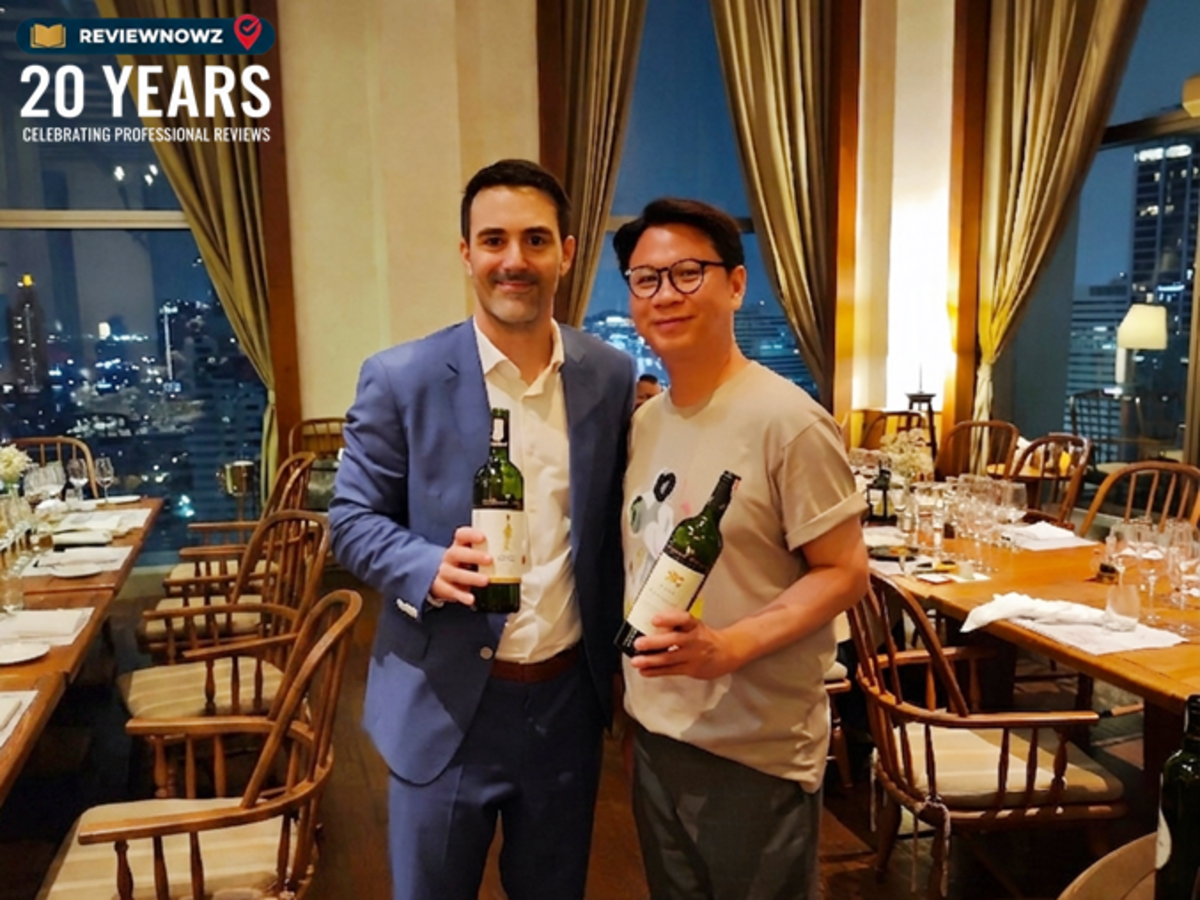 คุณ Jean-Clément Casse ยืนถ่ายภาพร่วมกับคุณโด้ ReviewNowz ขณะถือขวดไวน์ Bernard Magrez ในมืออย่างอบอุ่นและเป็นกันเอง บริเวณหน้าต่างกระจกบานใหญ่ชมวิวเมืองยามค่ำคืน ภายในห้องอาหาร Attico Cucina Italiana โรงแรม Radisson Blu Plaza Bangkok