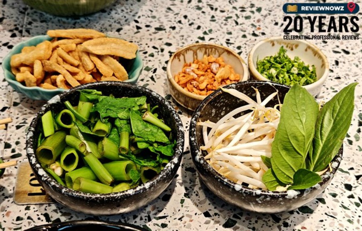 ชุดเครื่องเคียงก๋วยเตี๋ยวเรือ กากหมูเจียว ผักบุ้งลวก ผักสด ถั่วงอก และใบโหระพา จัดวางในถ้วยอย่างเป็นระเบียบ ร้านก๋วยเตี๋ยวเรือทองสมิทธ์ สาขาพาร์คสีลม ReviewNowz