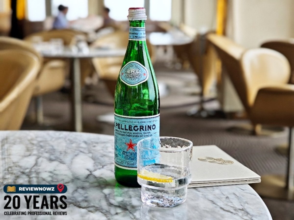 ขวดน้ำแร่อัดแก๊สธรรมชาติ S.Pellegrino Sparkling Natural Mineral Water วางคู่กับแก้วน้ำใส่เลมอนสไลซ์บนโต๊ะหินอ่อน ร้าน OJO Bangkok ชั้น 76 โรงแรม The Standard, Bangkok Mahanakhon ReviewNowz