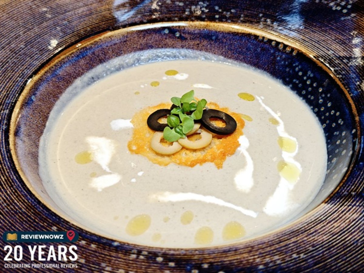 ครีมซุปแก่นตะวัน PEARL VELOUTÉ ท็อปด้วยพาร์เมซานชีสกรอบ มะกอกดำ และโฟมไวท์ทรัฟเฟิล ตกแต่งด้วยแผ่นทองคำแท้ เสิร์ฟในจานเซรามิก ณ ห้องอาหาร Club Ruby โรงแรม AIDEN SURAWONG BANGKOK ReviewNowz
