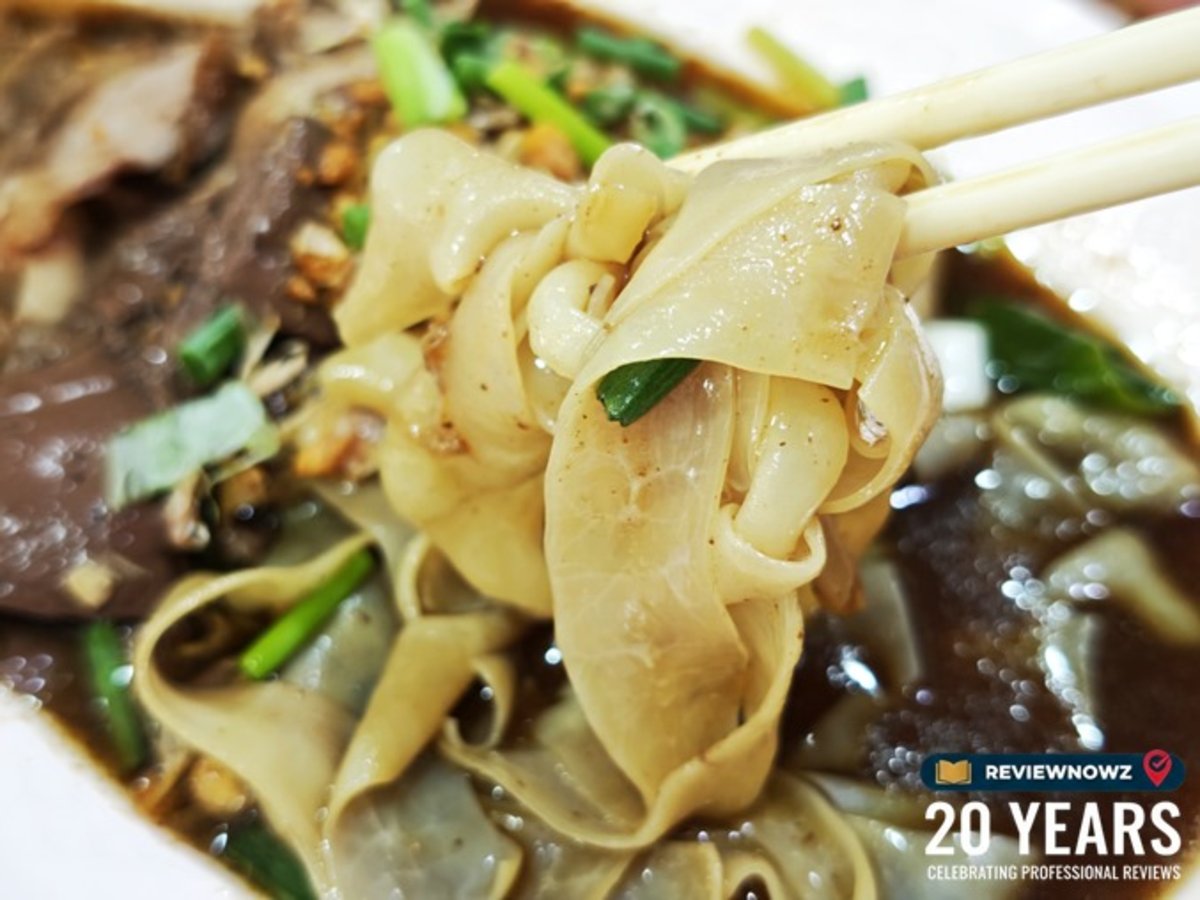 ภาพใช้ตะเกียบคีบไส้แก้วเป็ดใสกรอบชิ้นใหญ่ฉ่ำน้ำพะโล้ ของร้านก๋วยเตี๋ยวเป็ดเต้นระบำ ย่านคลองเตย ถนนพระราม 4 แสดงเนื้อสัมผัสความกรอบสะอาดและเลือดเป็ดนุ่มละมุน ReviewNowz