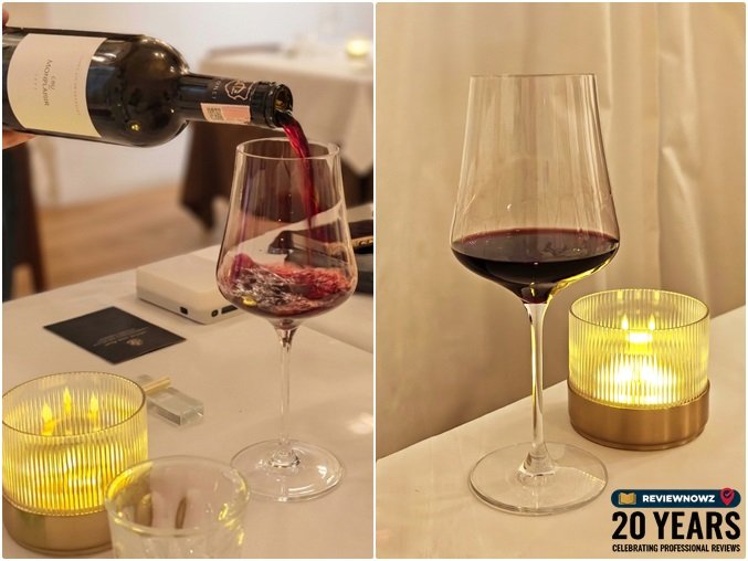 การเทไวน์แดง Gonet-M?deville Cru Monplaisir Bordeaux Sup?rieur 2022 สีเข้มลงในแก้วไวน์ใสข้างโคมไฟบนโต๊ะอาหาร ร้านอาหาร ROSA ย่านเยาวราช ReviewNowz
