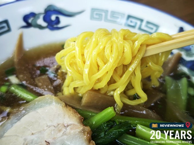 ใช้ตะเกียบหนีบเส้นราเมนสีเหลืองสดใสเหนียวนุ่มขึ้นมาจากชามซุป พร้อมหมูอบและผักกวางตุ้ง ร้าน ราเมงเทอิ สาขาสุรวงศ์ (Ramen Tei Surawong) ReviewNowz
