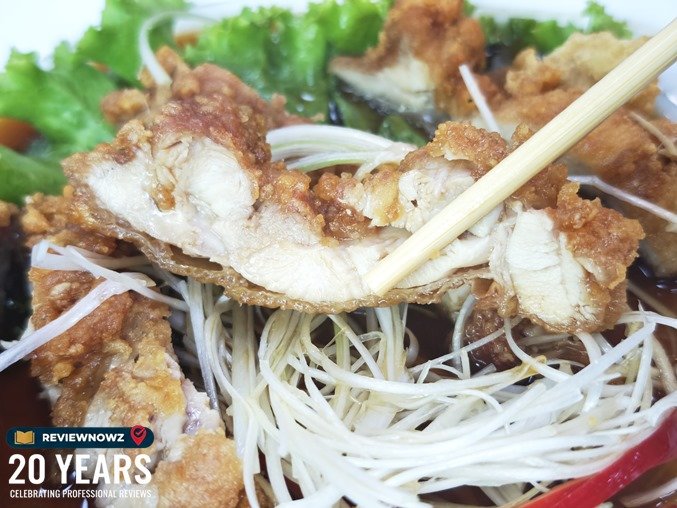ใช้ตะเกียบหนีบชิ้นไก่ทอดชิ้นหนานุ่มโชว์เนื้อด้านใน ราดน้ำซอสและผักซอย ร้าน ราเมงเทอิ สาขาสุรวงศ์ (Ramen Tei Surawong) ReviewNowz