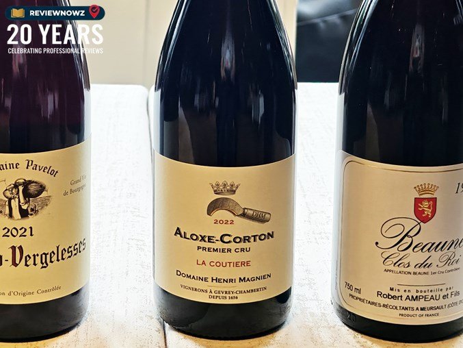 ขวดไวน์แดงไฮไลต์ยอด 2022 Henri Magnien Aloxe-Corton 1er Cru La Coutiere โดดเด่นอยู่ตรงกลางระหว่างขวดไวน์พรีเมียมอื่นๆ ในงาน Burgundy by Way of Bangkok จัดโดย Wine Garage ReviewNowz