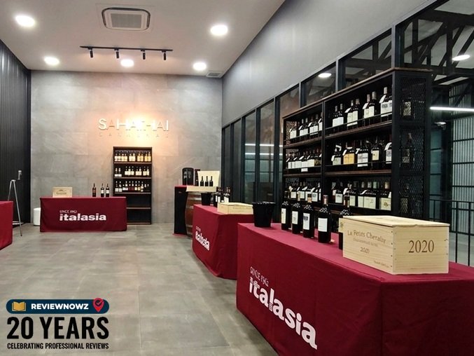 ห้องรับรองและจัดแสดงไวน์พรีเมียมของ ITALASIA ภายในศูนย์ LEO COLDBOTIC ตกแต่งด้วยโต๊ะคลุมผ้าสีแดงสลับขาว ชั้นวางขวดไวน์ และลังไม้โชว์สินค้า ReviewNowz