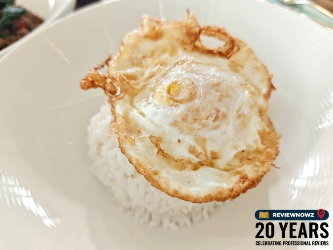 ข้าวสวยหอมมะลิร้อนๆ ท็อปด้วยไข่ดาวทอดกรอบสไตล์ไทย จัดวางในชามทรงสูงสีขาว สำหรับทานคู่กับผัดกะเพราเนื้อ ห้องอาหารเดอะ เวอรันดา โรงแรมแมนดาริน โอเรียนเต็ล กรุงเทพ ReviewNowz